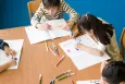 Children colouring a book on a table