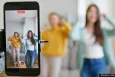 Two adolescents dancing in front of a smartphone on a tripod, recording themselves.