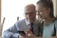 Elderly person looking at smartphone together with younger woman